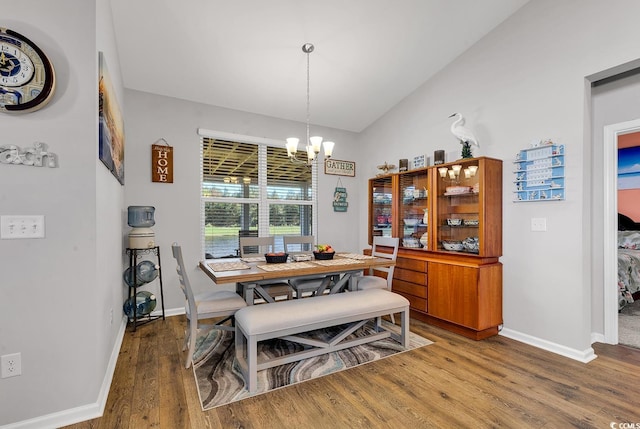 dining area featuring dark wood-type flooring, lofted ceiling, and an inviting chandelier