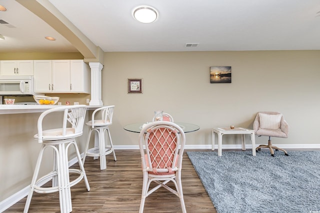 dining space with dark hardwood / wood-style flooring and decorative columns