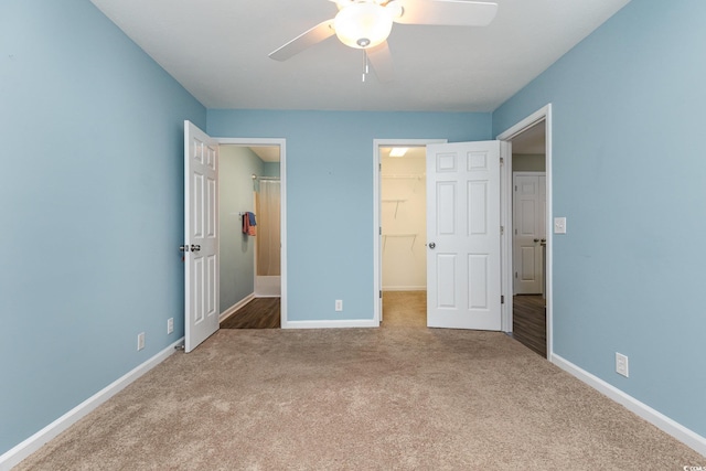 unfurnished bedroom with carpet, a spacious closet, ceiling fan, and a closet