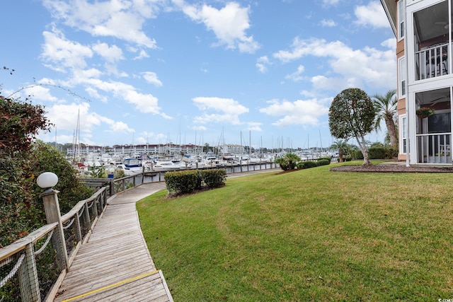 view of yard with a sunroom, a water view, and a boat dock