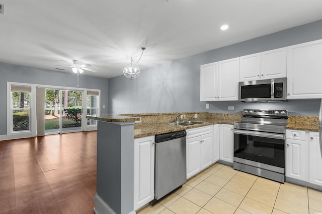 kitchen with dark stone counters, white cabinets, kitchen peninsula, sink, and appliances with stainless steel finishes