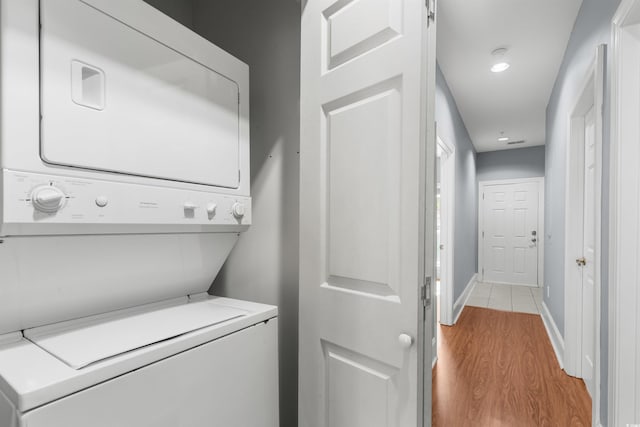 laundry area featuring stacked washing maching and dryer and light hardwood / wood-style flooring