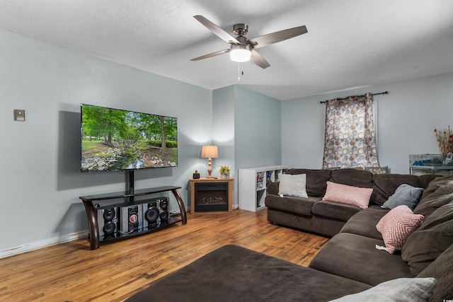 living room featuring a textured ceiling, wood-type flooring, and ceiling fan