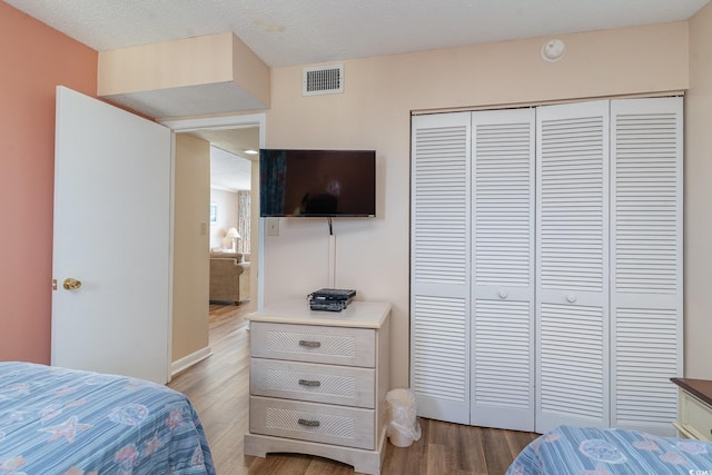 bedroom featuring hardwood / wood-style floors, a textured ceiling, and a closet