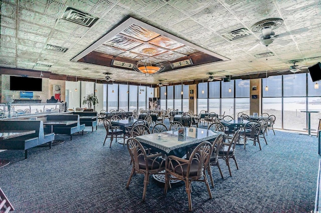 dining room featuring a wall of windows, dark colored carpet, and ceiling fan