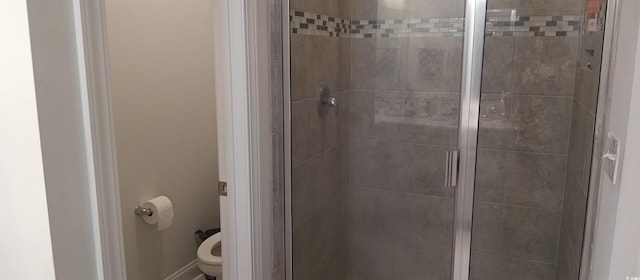 bathroom featuring toilet and a shower with door