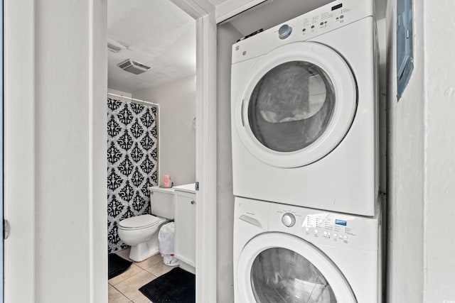 laundry room featuring light tile patterned floors and stacked washer and clothes dryer