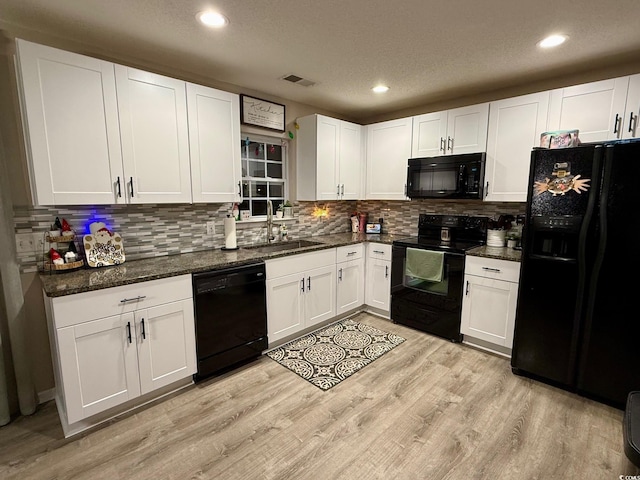 kitchen featuring dark stone counters, a textured ceiling, black appliances, light hardwood / wood-style flooring, and white cabinets