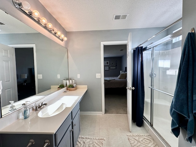 bathroom featuring a textured ceiling, tile patterned flooring, vanity, and a shower with door