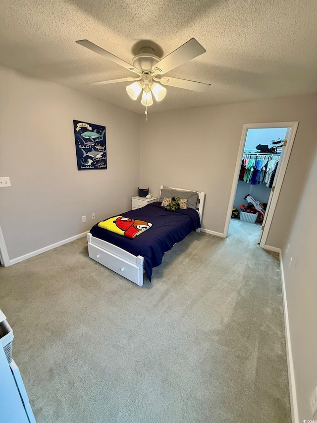 carpeted bedroom featuring ceiling fan, a textured ceiling, a closet, and a spacious closet