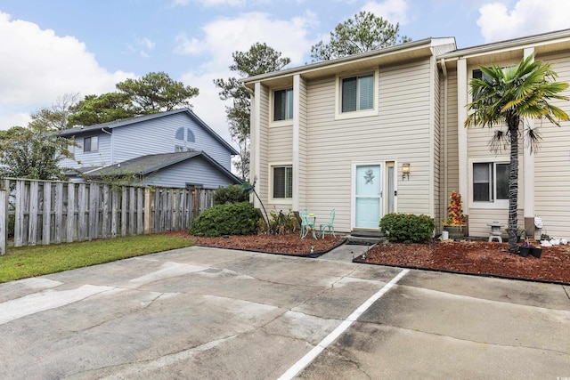 view of property featuring entry steps, uncovered parking, fence, and a patio