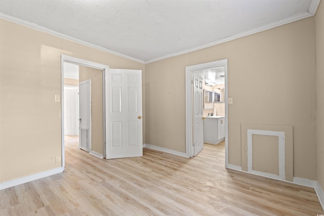 empty room with ornamental molding, a textured ceiling, and light wood-type flooring