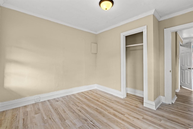 unfurnished bedroom with light wood-type flooring, ornamental molding, and a closet