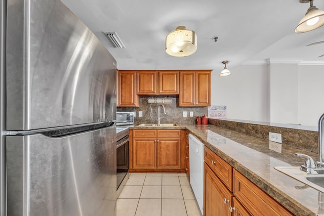 kitchen featuring light tile patterned flooring, crown molding, stainless steel refrigerator, sink, and kitchen peninsula