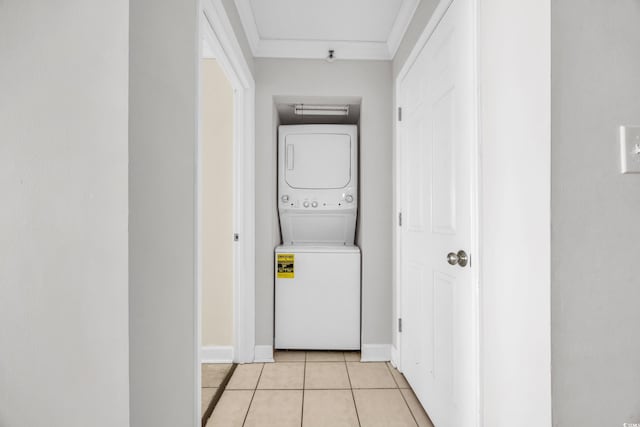 laundry room with stacked washing maching and dryer, light tile patterned floors, and ornamental molding