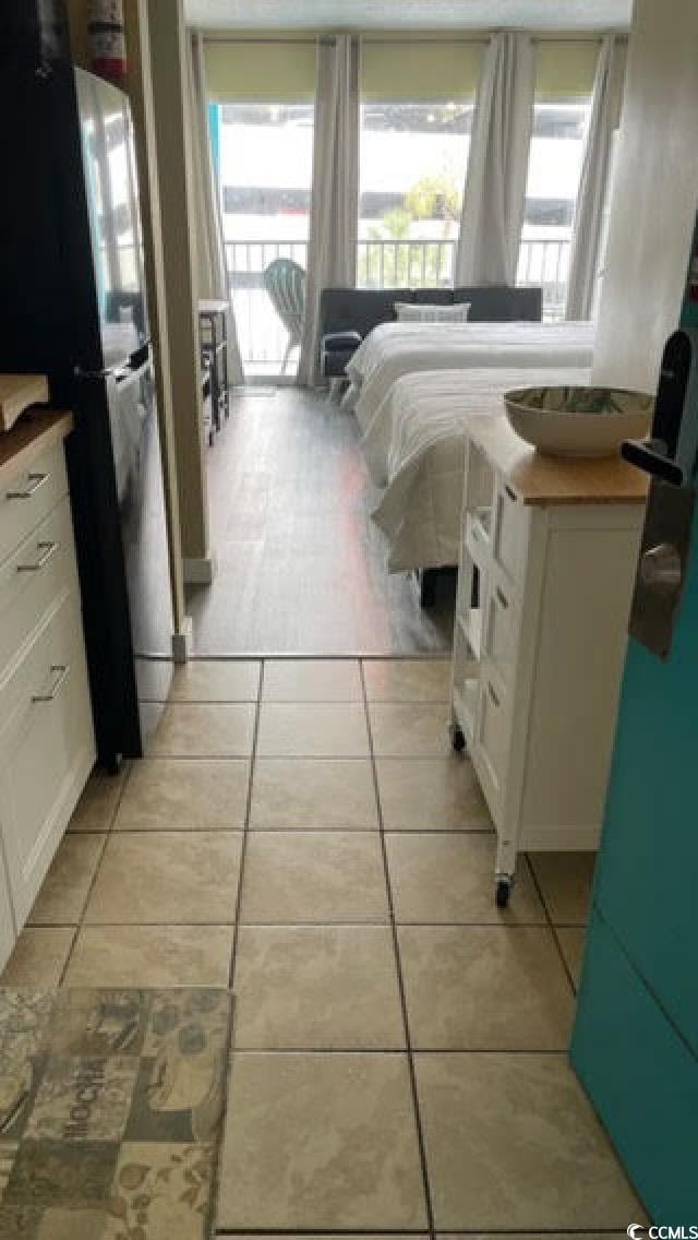 bedroom featuring black refrigerator, multiple windows, and light tile patterned floors