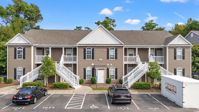 view of building exterior with uncovered parking and stairway