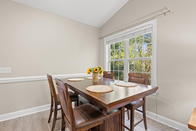 dining space featuring lofted ceiling, light wood-type flooring, and baseboards