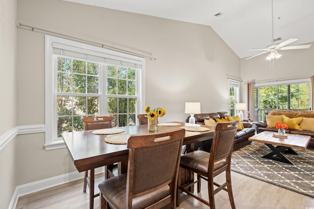 dining space featuring light wood-style floors, visible vents, vaulted ceiling, and baseboards