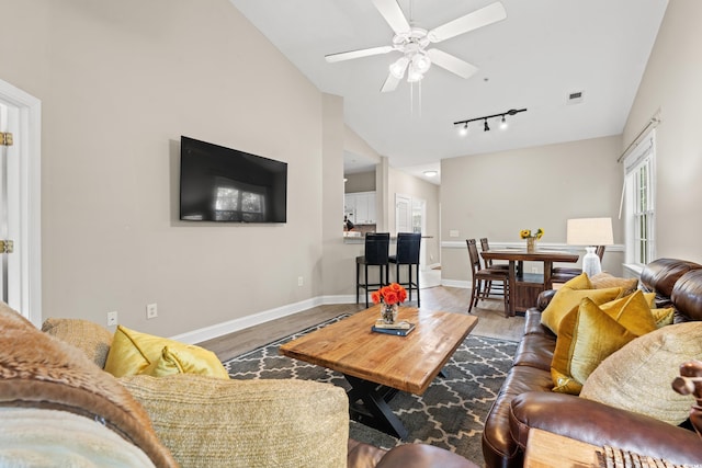 living room with visible vents, ceiling fan, vaulted ceiling, wood finished floors, and baseboards