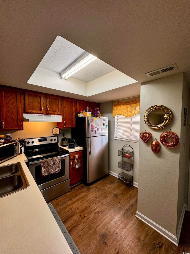 kitchen with sink, appliances with stainless steel finishes, a textured ceiling, a raised ceiling, and dark wood-type flooring