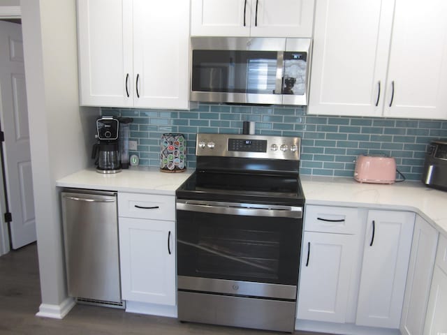 kitchen with white cabinetry, stainless steel appliances, dark hardwood / wood-style floors, and light stone counters