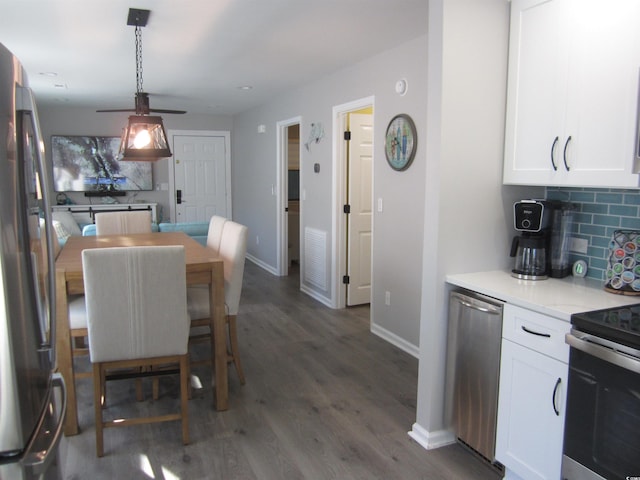 kitchen with white cabinetry, appliances with stainless steel finishes, dark wood-type flooring, and backsplash