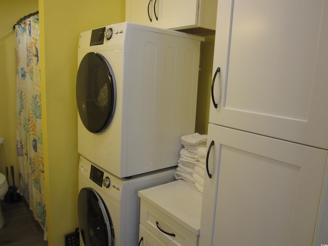 laundry area with hardwood / wood-style flooring and stacked washer and clothes dryer