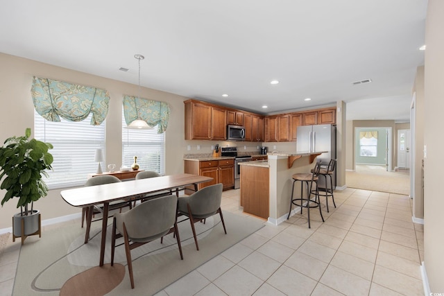 kitchen featuring appliances with stainless steel finishes, a healthy amount of sunlight, pendant lighting, and light tile patterned floors