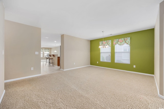 empty room with an inviting chandelier and light carpet