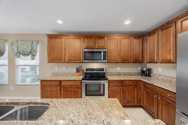 kitchen featuring light stone countertops, light tile patterned floors, stainless steel appliances, and sink