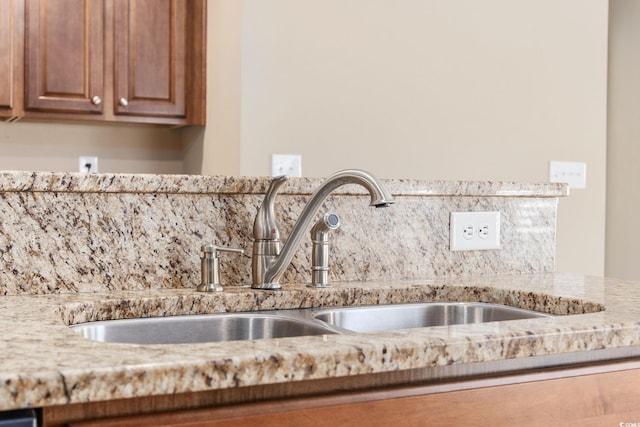 details with sink, light stone counters, and decorative backsplash