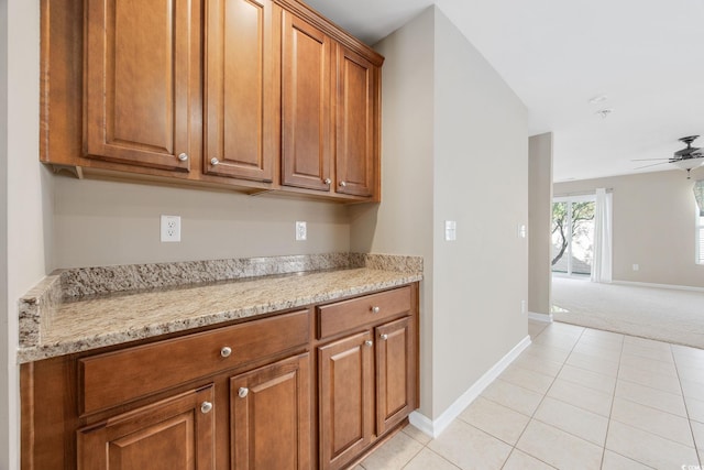 kitchen featuring light tile patterned floors, light stone countertops, and ceiling fan