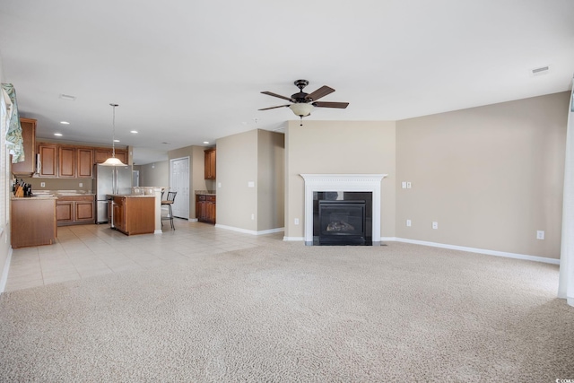 unfurnished living room featuring light colored carpet and ceiling fan