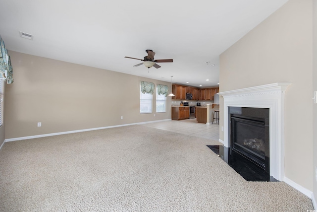 unfurnished living room featuring light carpet and ceiling fan