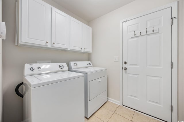 clothes washing area featuring washing machine and dryer, cabinets, and light tile patterned flooring