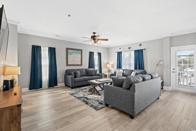 living area with light wood-style flooring, ornamental molding, and a wealth of natural light