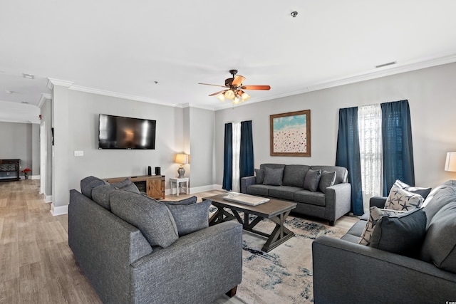 living area featuring light wood-style flooring, baseboards, and ornamental molding