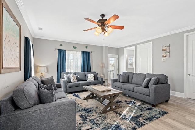 living room featuring baseboards, visible vents, a ceiling fan, ornamental molding, and light wood-type flooring