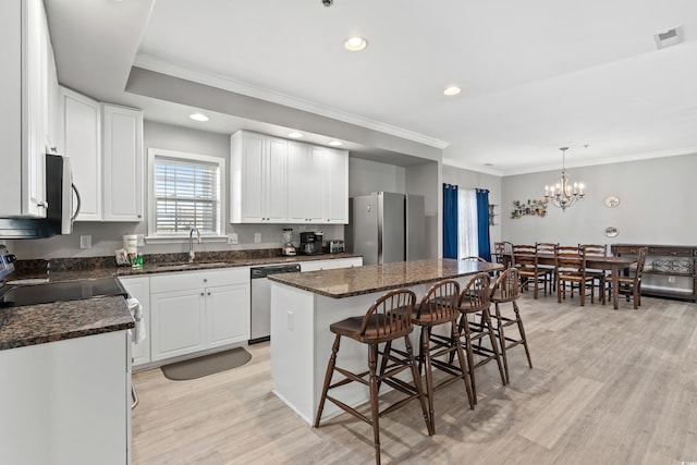 kitchen with a breakfast bar area, a center island, stainless steel appliances, white cabinetry, and a sink