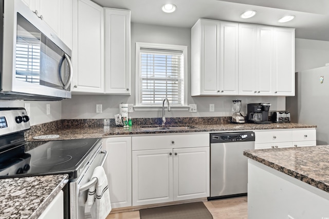 kitchen featuring recessed lighting, stainless steel appliances, a sink, white cabinets, and light wood finished floors