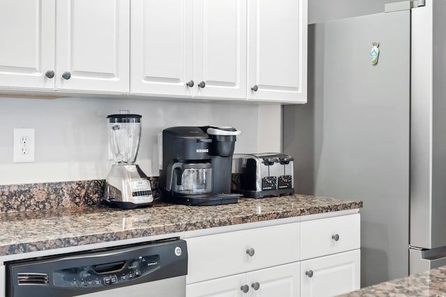 kitchen with dishwasher, dark stone countertops, freestanding refrigerator, and white cabinets