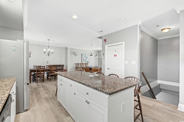 kitchen with light wood-type flooring, a kitchen island, a kitchen breakfast bar, and freestanding refrigerator