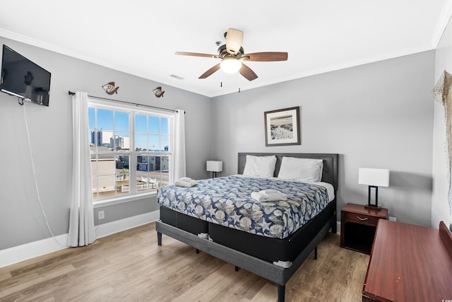 bedroom with ornamental molding, baseboards, visible vents, and light wood finished floors