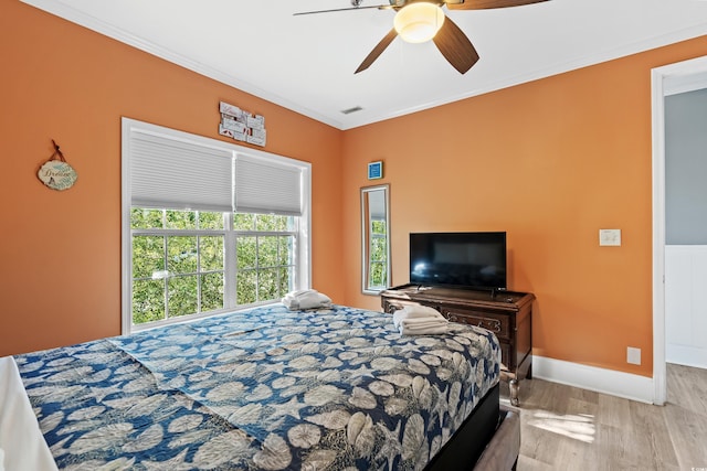 bedroom featuring baseboards, visible vents, a ceiling fan, ornamental molding, and wood finished floors