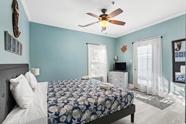 bedroom with baseboards, multiple windows, ornamental molding, and wood finished floors