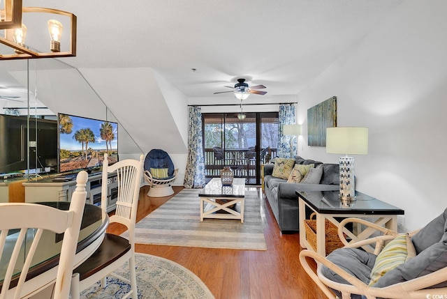 living room with ceiling fan with notable chandelier and wood-type flooring