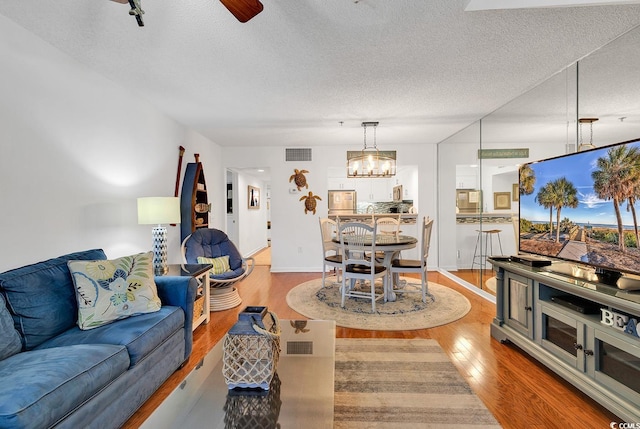 living room featuring an inviting chandelier, hardwood / wood-style floors, and a textured ceiling