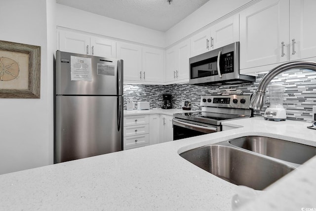 kitchen featuring decorative backsplash, stainless steel appliances, and white cabinets