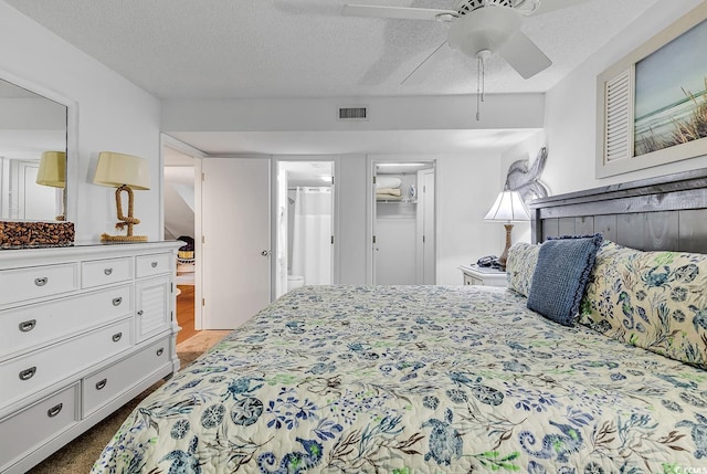 carpeted bedroom with ensuite bathroom, ceiling fan, and a textured ceiling